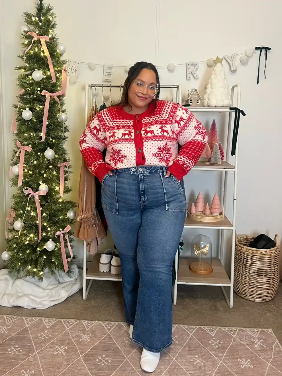Midsize woman wearing a red and white reindeer Christmas sweater with high rise blue jeans