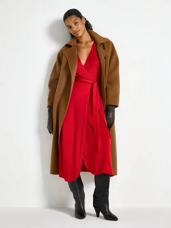 Woman wearing a red wrap midi dress with a camel coat and black boots for Christmas church