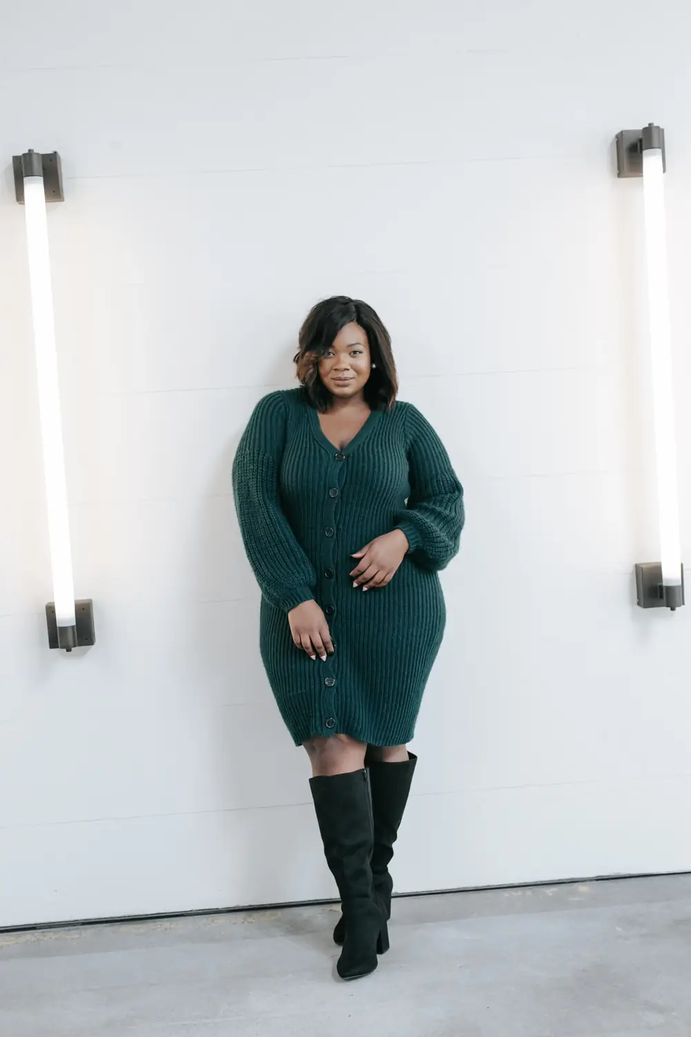 Midsize woman in a green ribbed sweater dress with black knee high boots for a winter date
