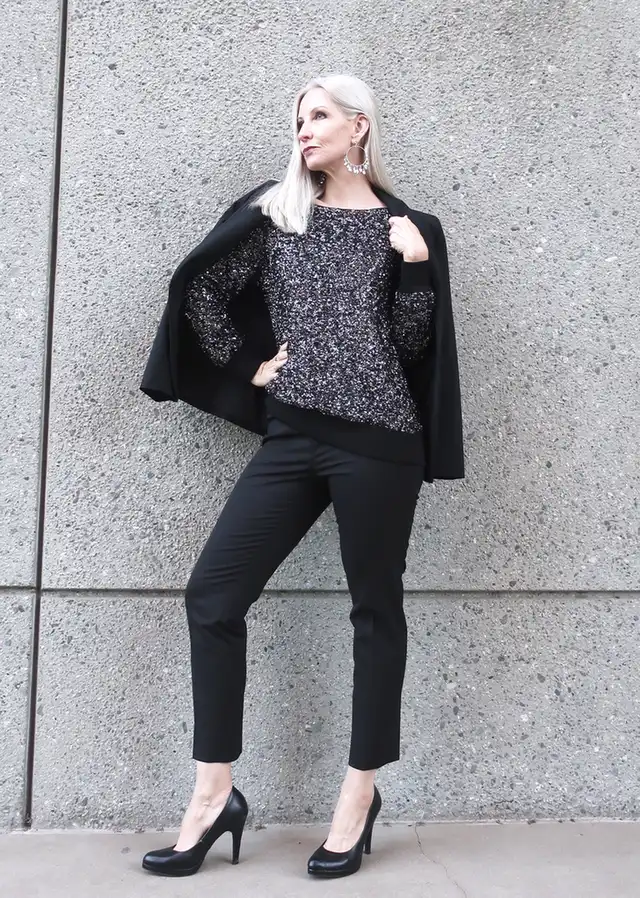 Silver haired woman wearing a black sequin sweater with tailored pants for New Year’s Eve