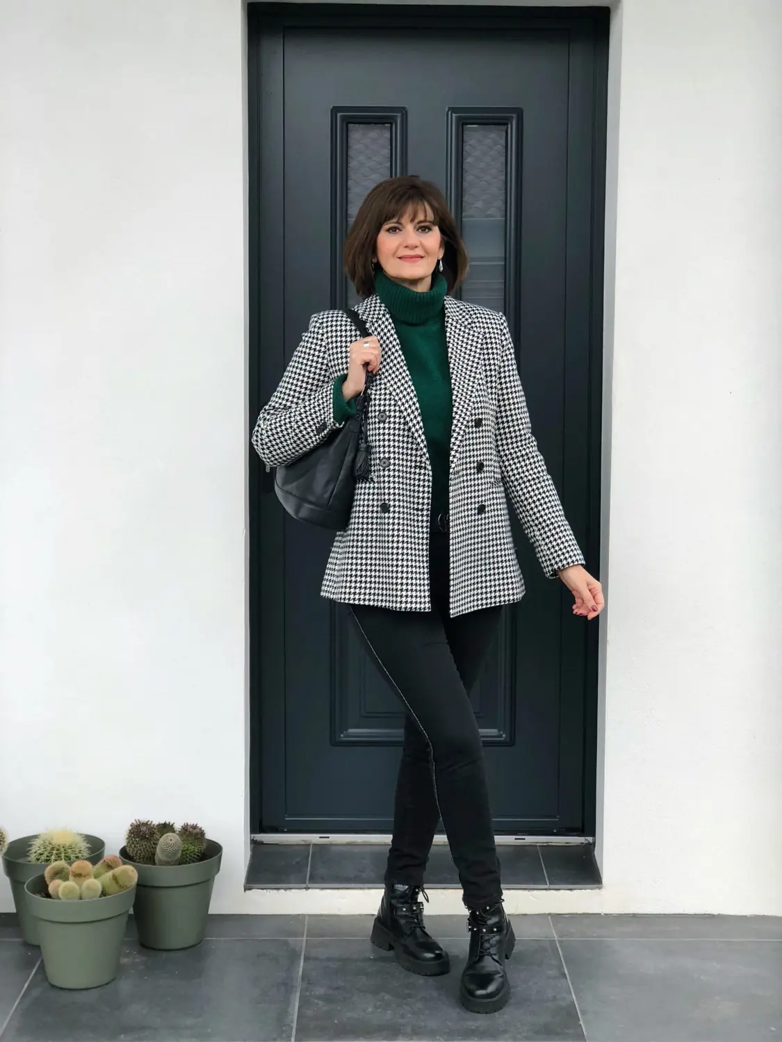 Mature woman wearing a plaid blazer over a turtleneck with dark jeans and winter boots