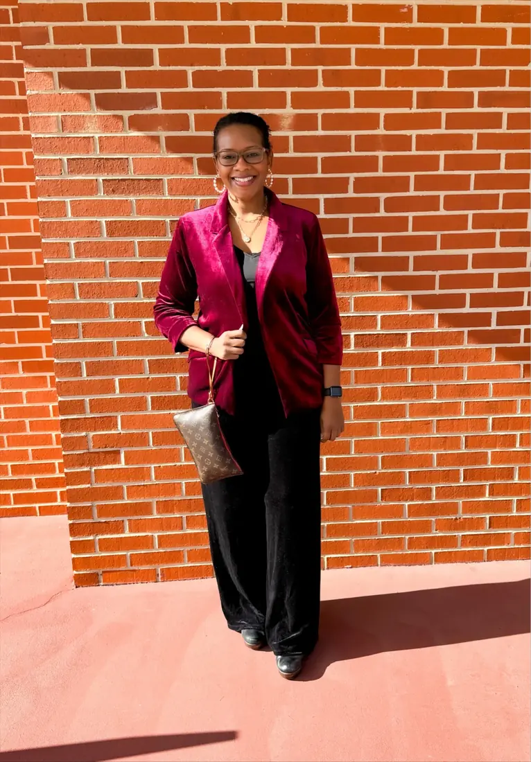 Woman wearing a burgundy velvet blazer with black trousers for a Christmas church service