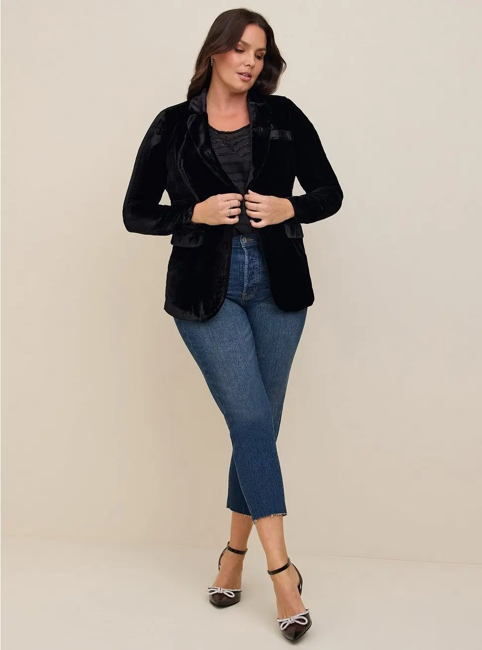Midsize woman wearing a velvet blazer with blue jeans and pointed heels for a casual winter date