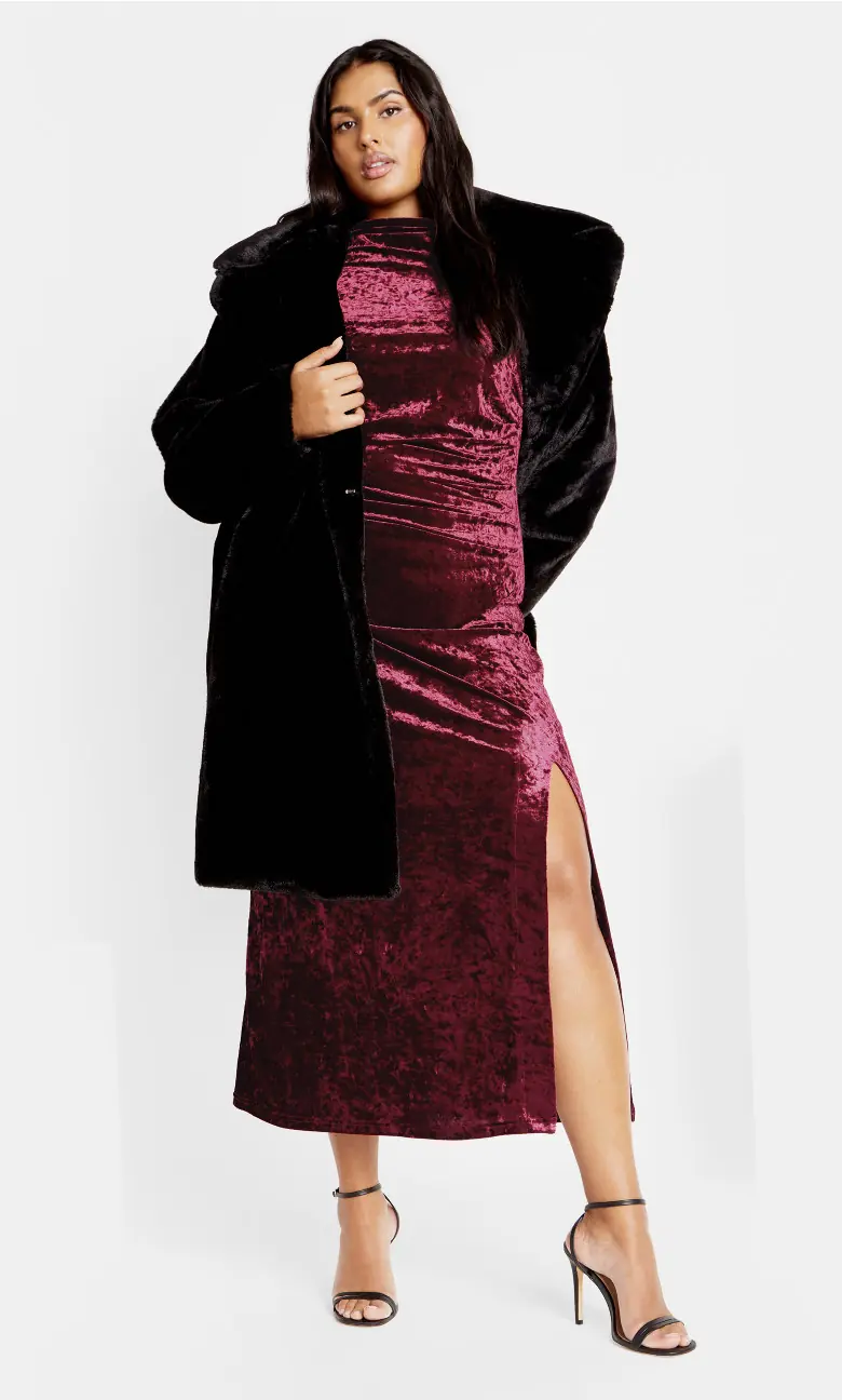 Curvy woman in a burgundy velvet midi dress with a black faux fur coat for winter date night