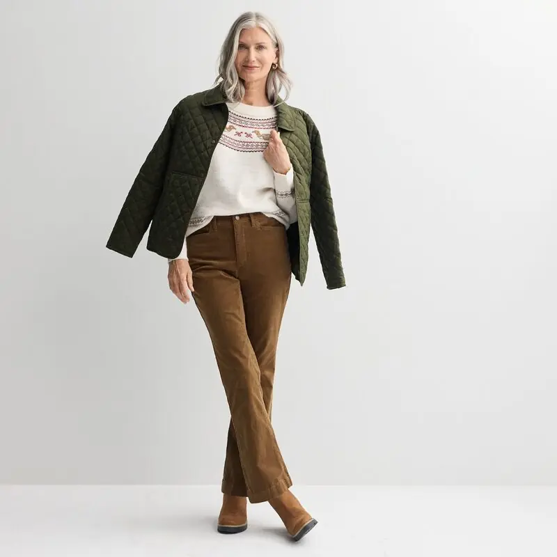 Mature woman in an olive quilted coat with a soft sweater and rust corduroy trousers