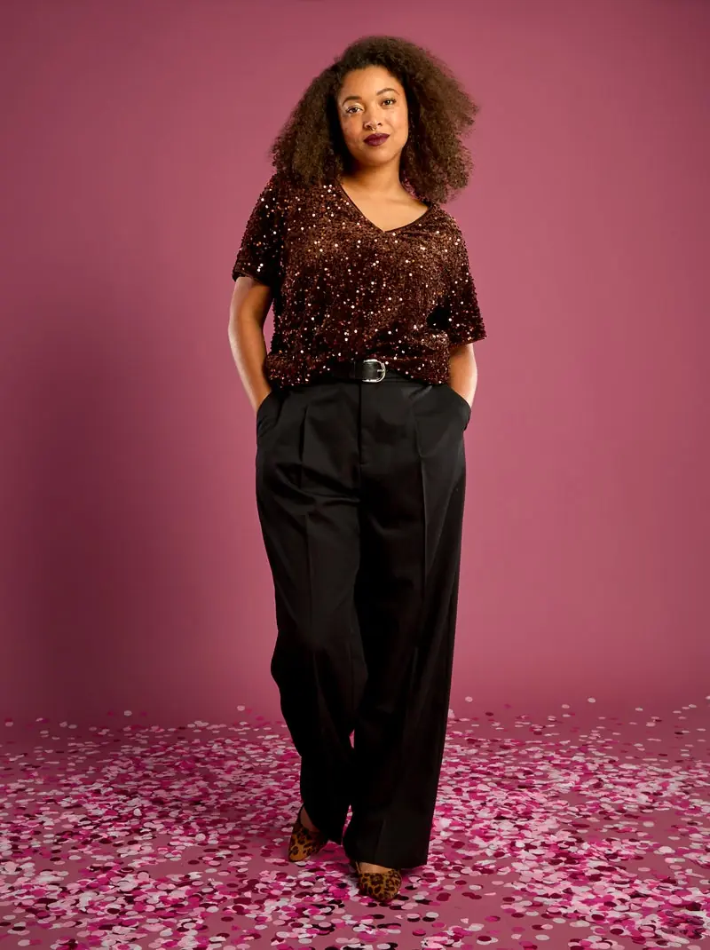 Plus size woman wearing a sequin top with black wide leg trousers for dinner and cocktails