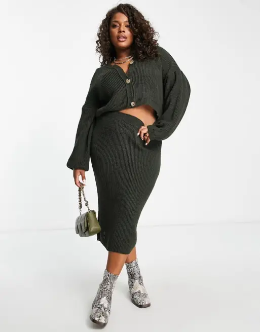 Plus size woman wearing a matching knit midi skirt and cropped cardigan with ankle boots