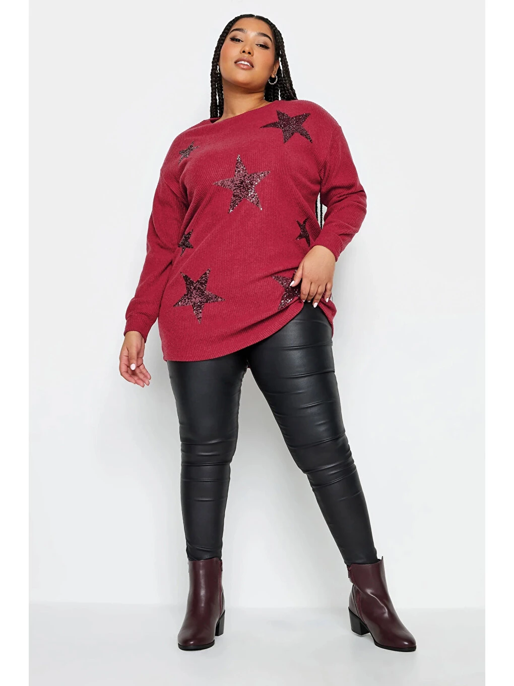 Plus size woman wearing a red star sweater with black faux leather leggings and burgundy boots