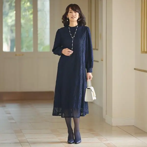Mature woman wearing a navy lace midi dress with a pearl necklace for Christmas church