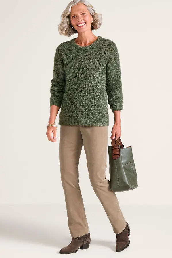Woman wearing a green cable knit sweater with khaki trousers and brown boots