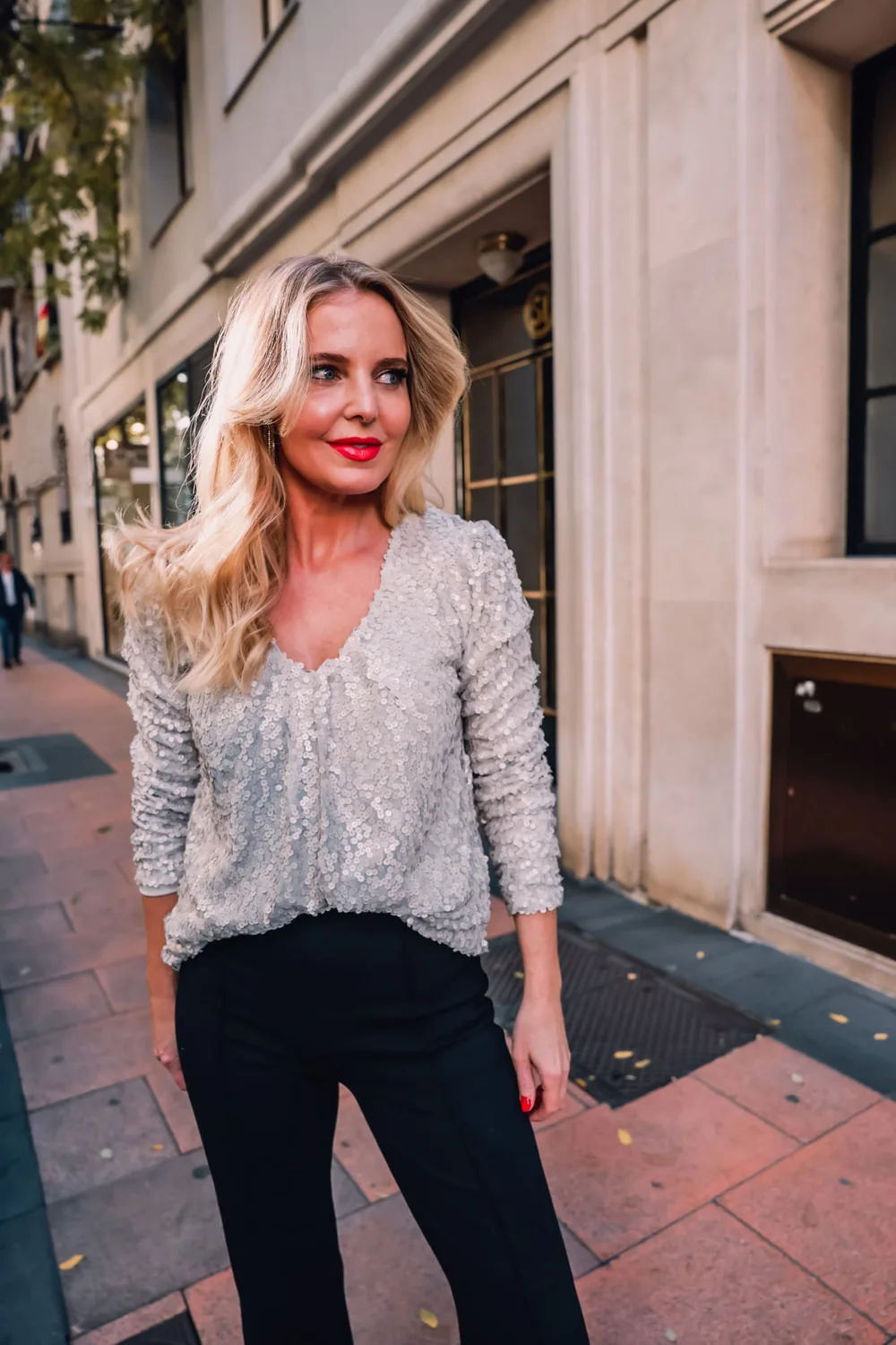 Woman wearing a silver sequin top with black wide leg trousers for a holiday office party