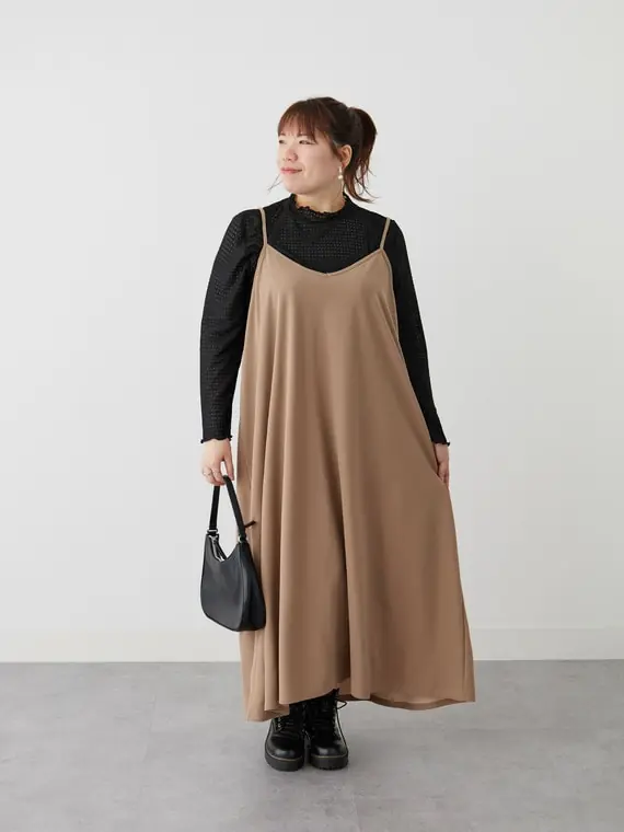 Curvy woman layering a brown slip dress over a fitted black turtleneck with ankle boots