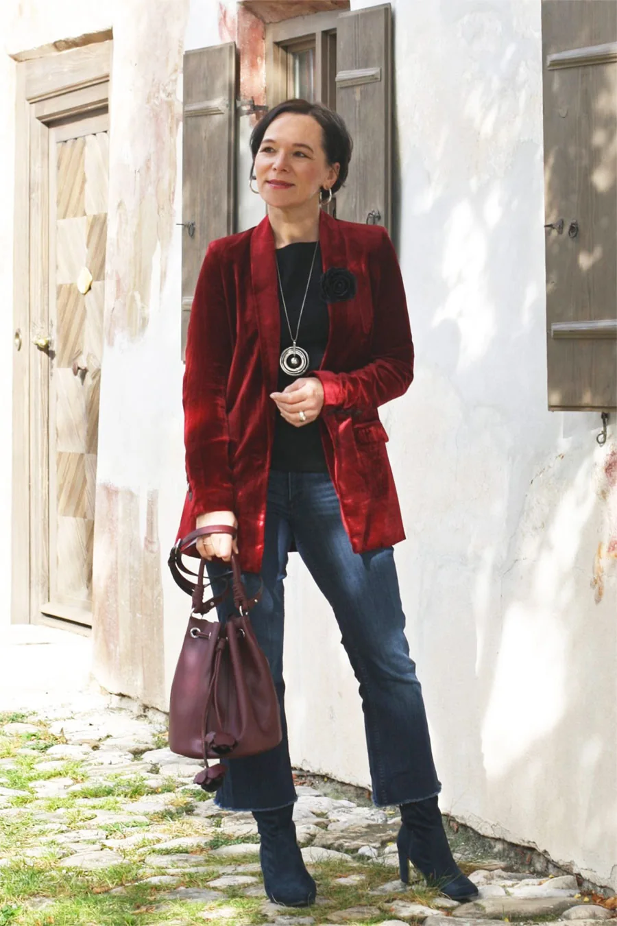 Woman wearing a wine velvet blazer with a black top dark jeans and ankle boots