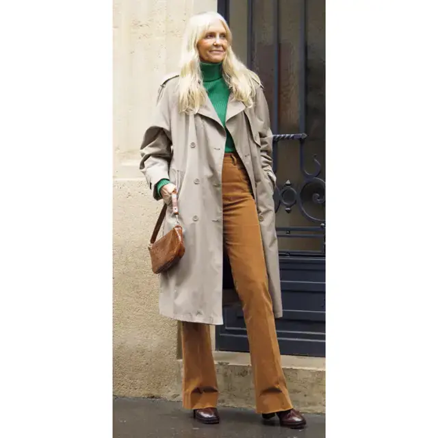 Woman wearing a beige trench with a green turtleneck and brown corduroy pants for winter city travel