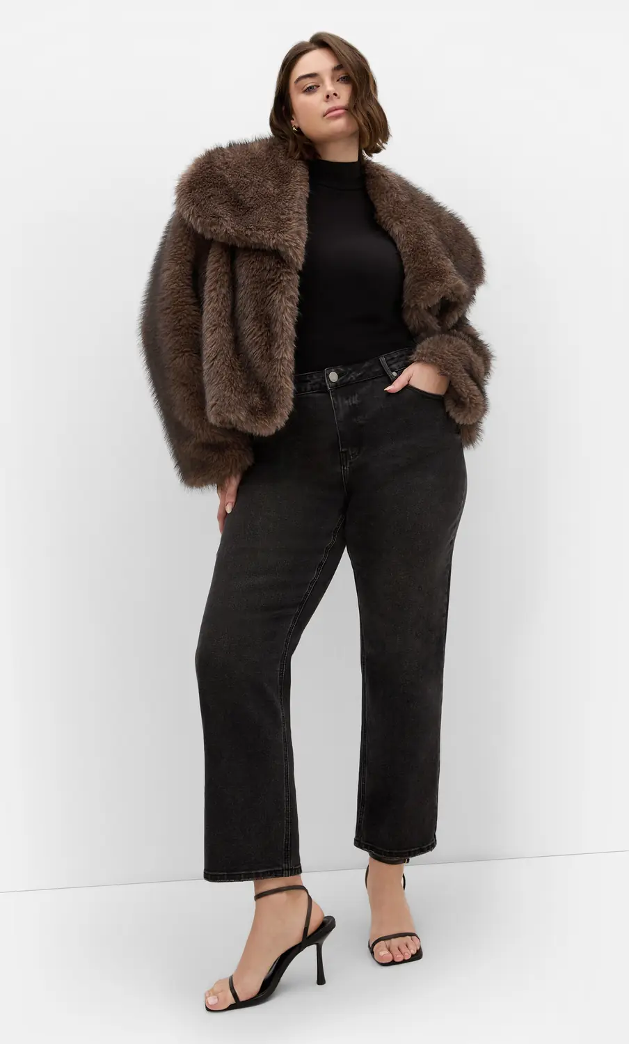 Plus size woman wearing a brown faux fur jacket with a black top and dark jeans for date night