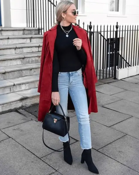 Woman styling a red wool coat with a black knit and dark jeans for a bold cold weather outfit