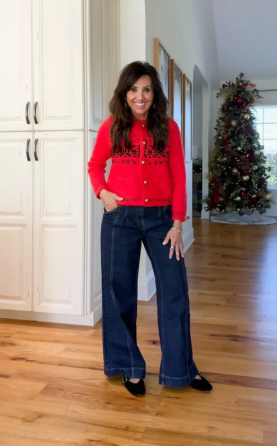 Woman wearing a red Fair Isle cardigan with dark wide leg jeans and black flats at Christmas