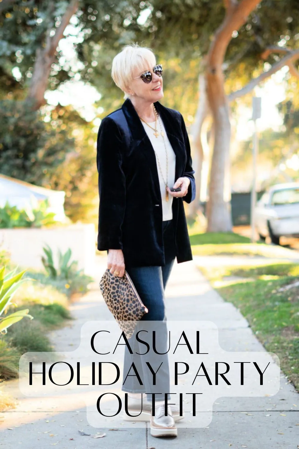 Woman wearing a black velvet blazer with a white top straight jeans and metallic shoes