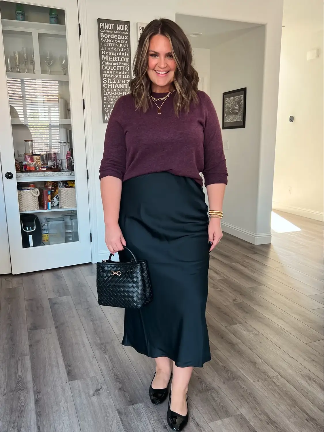Woman wearing a burgundy sweater with a black satin maxi skirt and patent flats