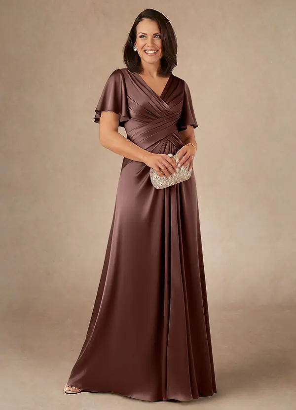 A woman wearing an espresso brown satin floor length A line gown with flutter sleeves and a silver clutch