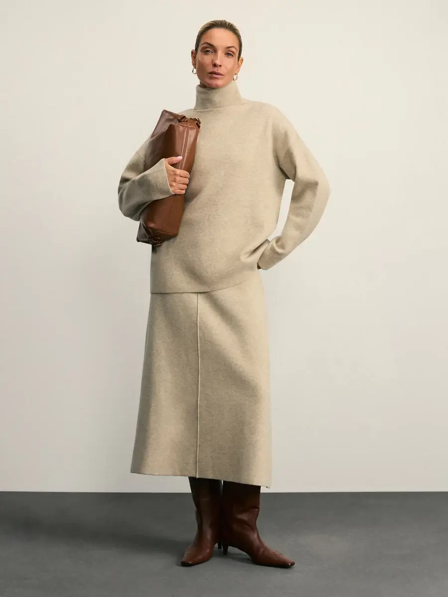 Elegant woman over 50 wearing a cashmere turtleneck with a midi skirt and tall boots