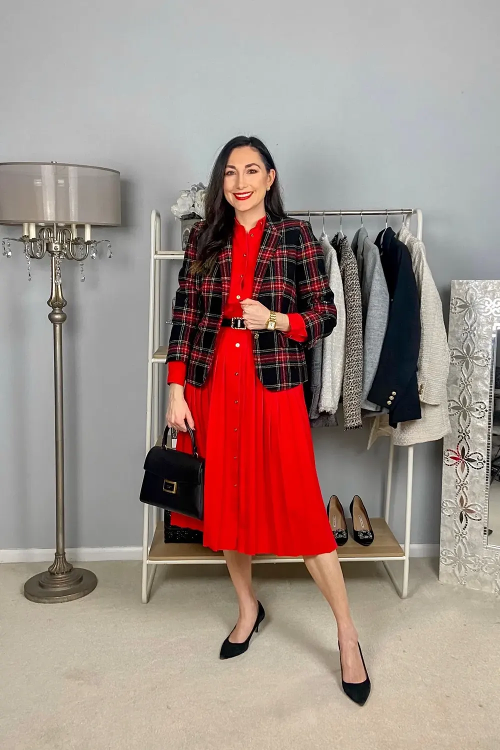 Woman wearing a red pleated midi dress with a black and red tartan blazer for a work party