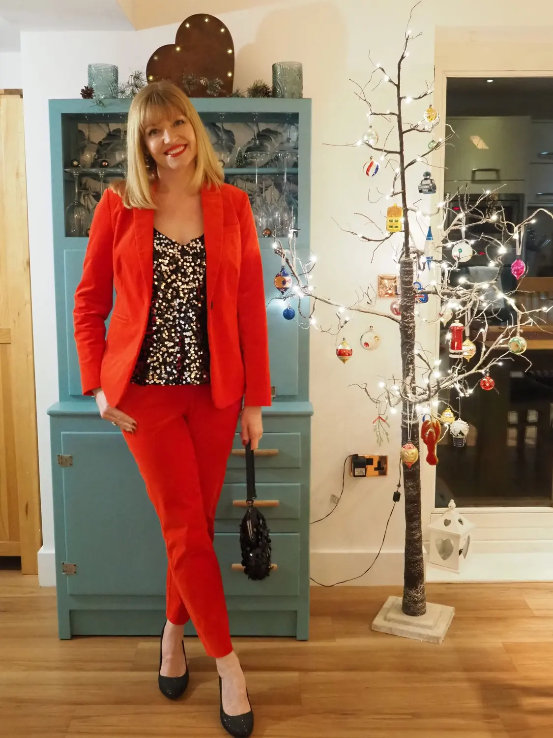 Woman wearing a red velvet pantsuit with a black sequin camisole for Christmas